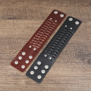 Détail de bracelets en cuir noir et marron tressé avec boutons-pression argentés