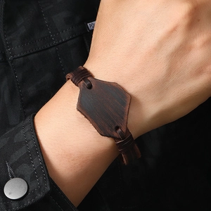 Dettaglio macro del bracciale in pelle intrecciata marrone con ciondolo esagonale retro