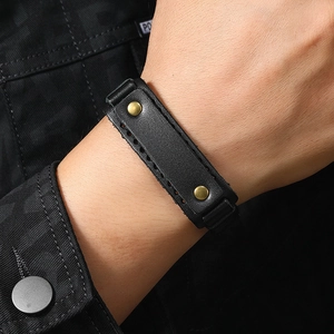 Macro shot of men's wide black leather bracelet with bronze rivets and punk styling