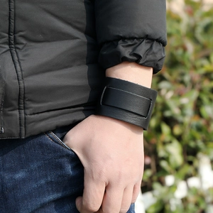 Gros plan d'un large bracelet punk en cuir noir avec boucle minimaliste porté à l'extérieur