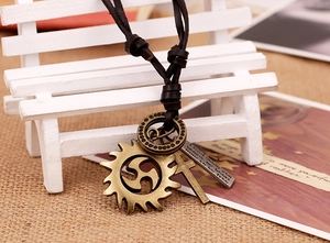 Close-up of vintage leather necklace with bronze gear, cross, and engraved metal charms