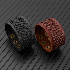 Dettaglio di bracciali in pelle intrecciata con bottoni a pressione in bronzo, nero e marrone