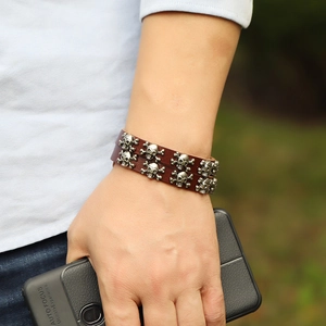 Close-up of double-wrap brown leather bracelet with silver skull studs on a man wrist