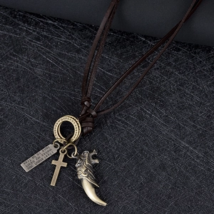 Détail de pendentifs éléphant et dent de loup en bronze sur collier de cuir tressé