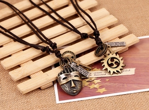 Detail of vintage bronze sun and mask pendants on adjustable brown leather cords