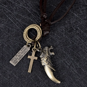 Détail du collier rétro en cuir avec dent de loup, croix en bronze et pendentif gravé