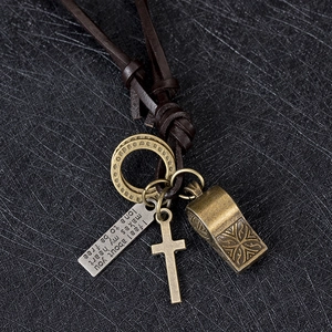 Dettaglio dei pendenti in ottone vintage con targhetta incisa e cordino in cuoio