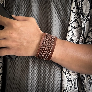 Dettaglio ravvicinato di un bracciale vintage in pelle intrecciata marrone da uomo