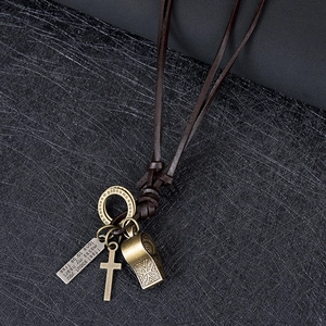 Dettaglio macro della collana vintage in pelle con fischietto in bronzo, croce e piastrine