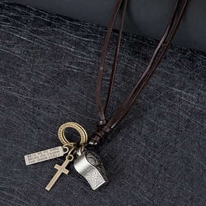 Dettaglio di collana in pelle vintage con fischietto d'argento e ciondoli a croce