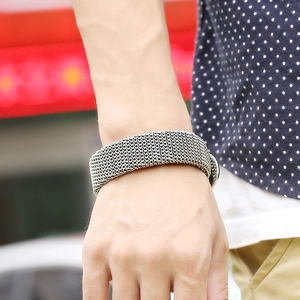 Silver wide mesh chain bracelet in industrial punk style on a male wrist with casual outfit