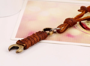 Macro shot of bronze wrench pendant with dark brown leather cord in vintage punk style