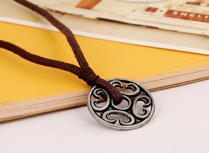 Macro shot of vintage style hollow round pendant with brown braided wax cord necklace