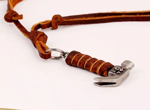 Macro shot of silver hammer pendant with skull relief on brown cowhide leather necklace