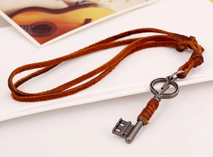 Close-up of vintage lightning key pendant on genuine leather cord over white plate
