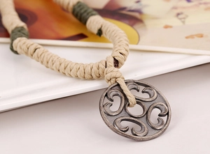 Close-up of ethnic handmade woven necklace with vintage bronze hollow pendant details