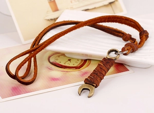 Close-up of vintage bronze wrench pendant wrapped in leather on a rustic leather cord