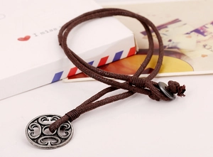 Macro detail of retro braided brown cord and circular hollow alloy pendant on postcards