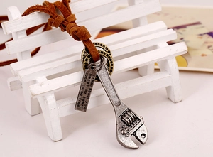 Macro detail of industrial punk wrench pendant with skull carving and leather cord