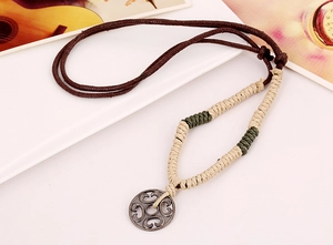 Macro detail of Bohemian woven necklace with vintage metal pendant and intricate knotwork