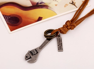 Macro detail of industrial wrench pendant with engraved tag on brown leather cord