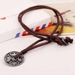 Vintage round metal pendant on dark brown wax cord necklace with retro patterns