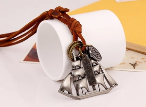 Macro detail of retro sailboat pendant with engraved plate on brown leather cord