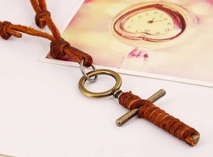 Detail of vintage leather cord necklace with brass cross pendant on a retro card
