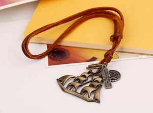 Close-up of vintage bronze sailboat pendant on adjustable brown leather cord necklace