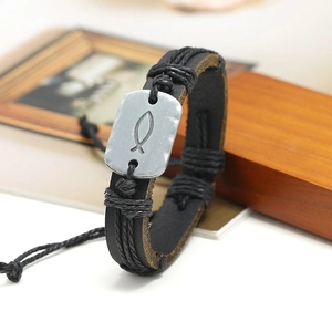 Detail of vintage braided black leather bracelet with silver fish symbol metal plate