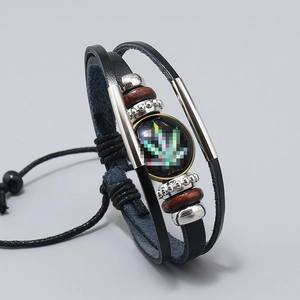 Macro detail of multilayer leather bracelet with maple leaf glass gem and metallic beads