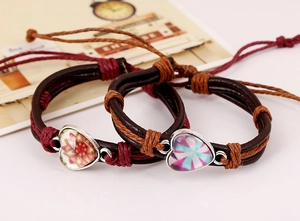 Dettaglio macro di bracciali in pelle multistrato con ciondolo in vetro a forma di cuore