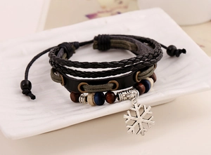 Dettaglio del bracciale multistrato in pelle con perline e ciondolo a fiocco di neve