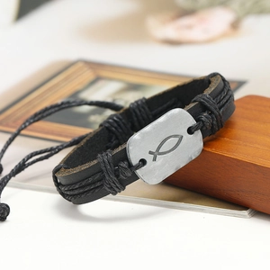 Detail of vintage braided leather bracelet with silver metal plate featuring Ichthys fish symbol