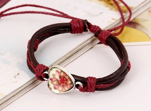 Dettaglio di un braccialetto bohémien in pelle intrecciata con ciondolo a cuore mandala