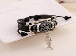 Detail eines mehrlagigen schwarzen Lederarmbands mit Silberanhängern und Fischgräten-Motiv