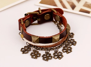 Macro detail of retro leather bracelet with bronze rivets and dangling clover charms