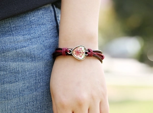 Dettaglio di un bracciale a cuore vintage con motivo mandala e cinturini in pelle