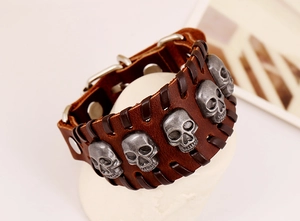 Detail view of brown braided leather cuff bracelet with five vintage silver skull charms