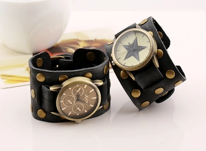 Close-up of wide black leather cuff watch bands with bronze rivets and punk star dial