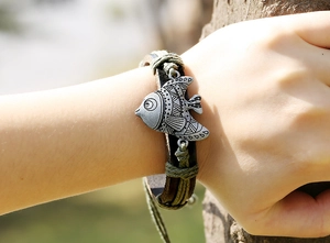 Détail macro du bracelet en cuir tressé à la main avec un pendentif poisson en alliage
