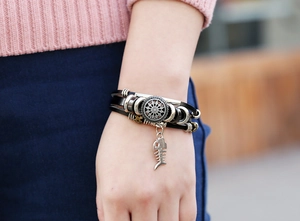 Detail eines mehrlagigen Lederarmbands mit Silberperlen und Fischgräten-Anhänger