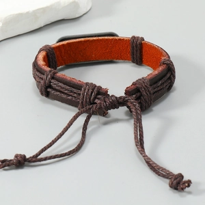 Détail d'un bracelet en cuir marron foncé tressé à la main avec cordon réglable et plaque