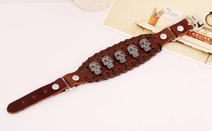 Detail of brown leather punk bracelet featuring five silver skull studs and buckle closure