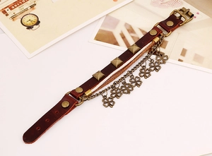 Close-up of vintage brown leather bracelet with bronze clover charms and metal rivets