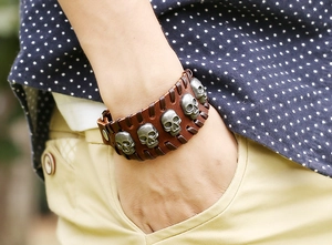 Detail of wide brown leather bracelet with five silver skull studs on a wrist