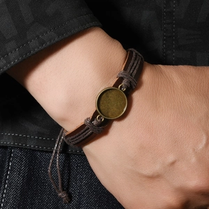 Handgewebtes PU-Lederarmband mit Vintage-Bronze-Basis am Handgelenk vor Denim-Hintergrund