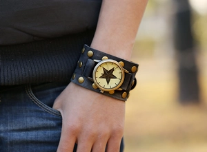 Close-up of a punk-style wide leather cuff watch with brass rivets and star dial