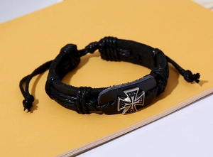 Close-up of black leather woven bracelet featuring a silver metal cross and adjustable cord