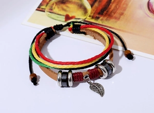 Macro detail of multi-layer leather bracelet featuring a metal leaf charm and braided ropes